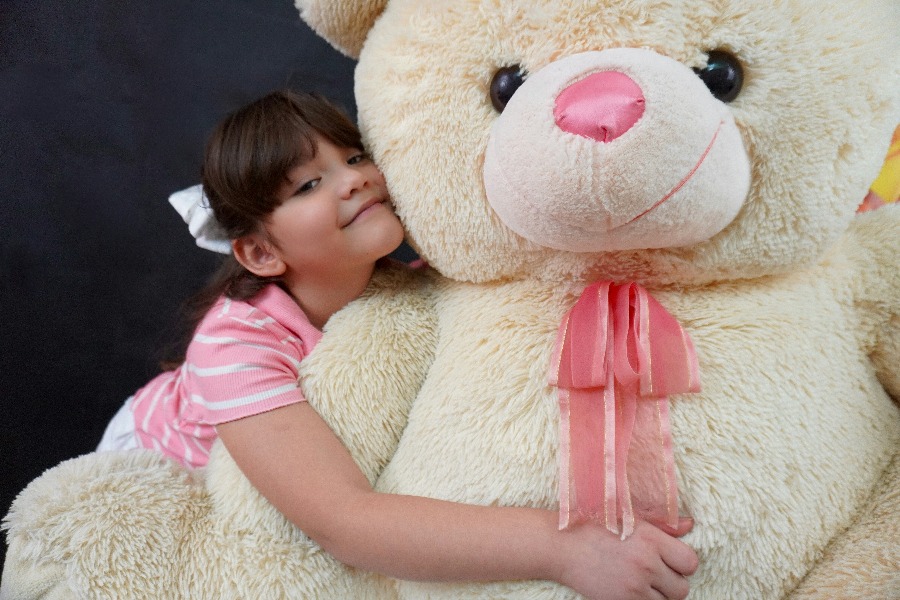 Kind drückt einen Teddybären an sich, Sinnbild für das Krafttier, das dem Kind Schutz gibt.
