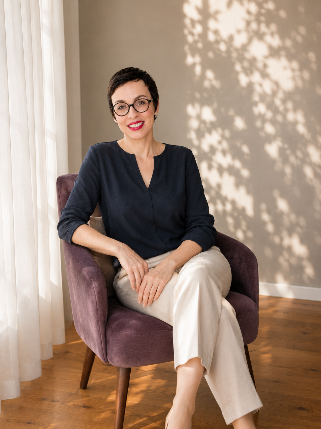 Katja Fesselman von schräg vorne an einem Geländer lehnend. Schwarze Brille, kurze Haare und kurzärmliches Shirt